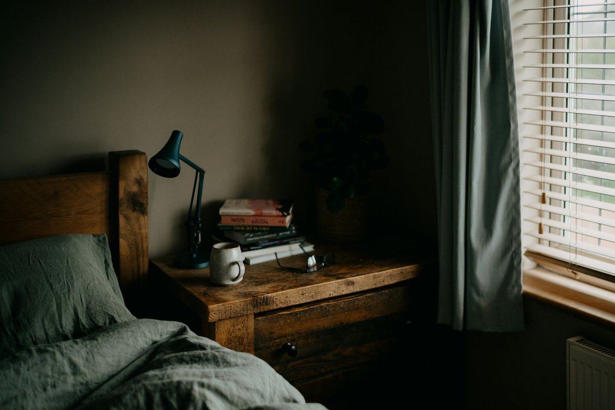 Empty bed beside a lamp and window