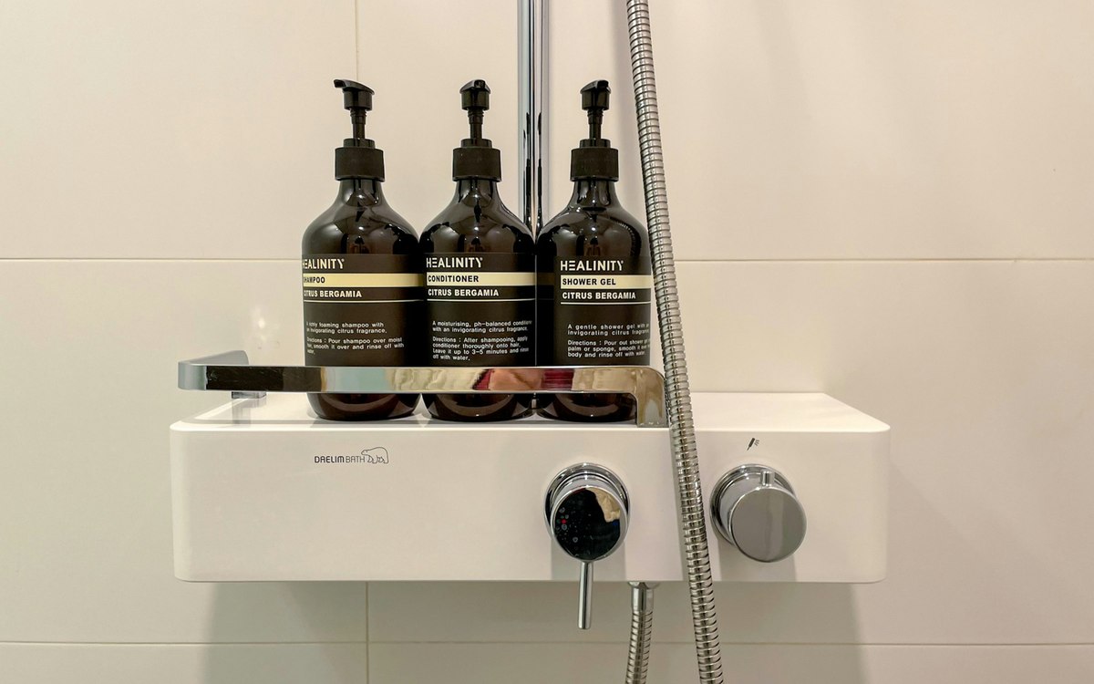Three pump bottles on a shower shelf