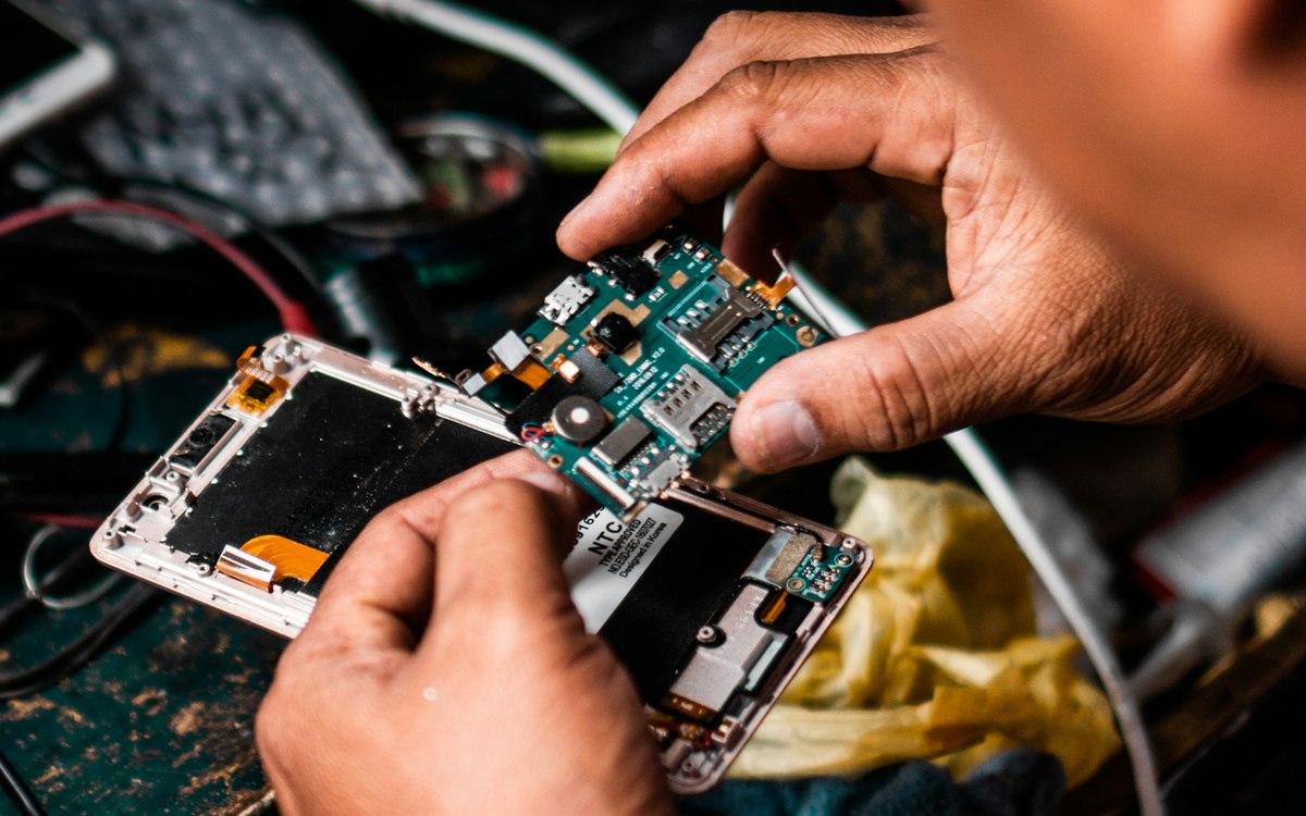 Hands repairing a smartphone on an electronics workbench